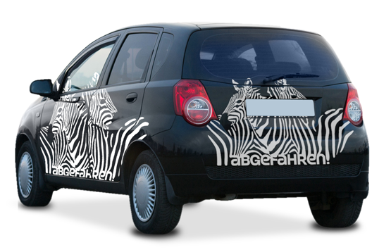 Schwarzes Auto mit zwei Zebras als weiße Streifen aufgeklebt