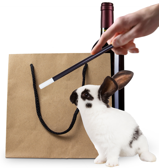 Hase, Papiertasche und Weinflasche stehen beieinander und im Vordergrund ist eine Hand mit Zauberstab